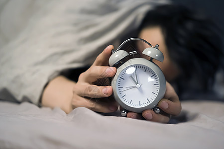 毯子下面的年轻人手握着一个古老的闹钟快乐小时手表男生压力就寝枕头倒数睡眠时间图片