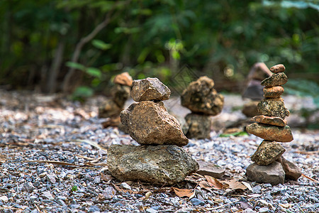 上山人行道上的平衡石塔 背景是绿色植物石头岩石森林叶子花园治疗重力卵石艺术树叶图片