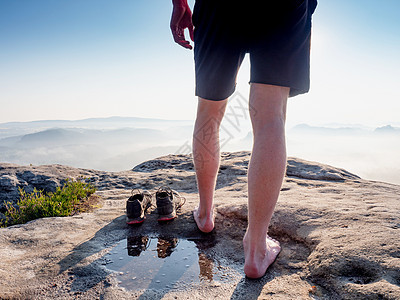 在沙石岩边的岩石边缘上 鞋和水坑被取下来旁边的希克人享受着风景悬崖顶峰小路空气远足者人行道冒险远足山脉赤脚图片