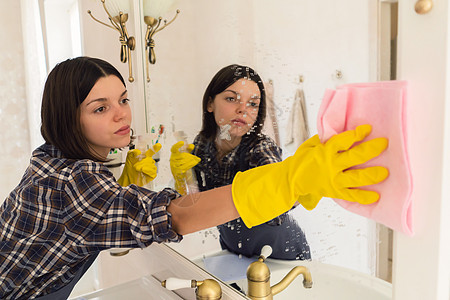年轻女人在浴袍里洗镜子家庭工作消毒女士洗涤剂抹布快乐笑脸房子服务图片