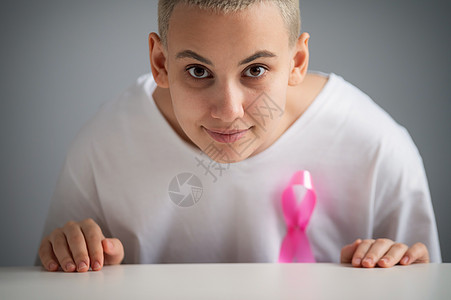 白色T恤上贴着粉红色丝带的金发短发女人 在白色背景上象征着乳癌卫生机构疾病保健胸部信仰治疗外科手术女性图片