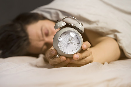 毛毯下一个年轻人的手 在灰色处握着闹钟就寝男生考试睡眠快乐枕头时间卧室小时倒数图片