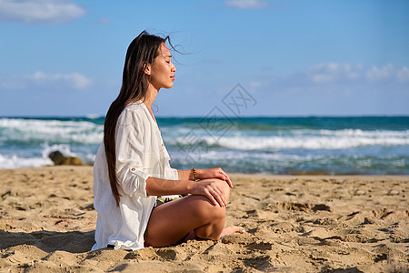 在沙滩上冥想时 处于莲花姿势的年轻美女女性海洋海景精神女孩身体闲暇海滩蓝色活力图片