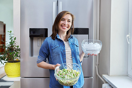笑女人手里拿着一碗冰和蔬菜沙拉盘子小吃冷藏食物房子厨房冻结饮食营养饥饿冰箱图片