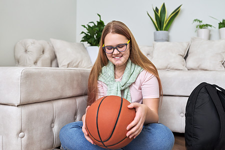 快乐笑笑笑的少女 带着篮球在家中坐在地板上手握着篮球图片