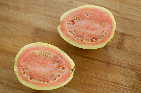 新鲜有机成熟的红番石榴果实在木板上切成两半 异国情调的水果健康饮食概念图片