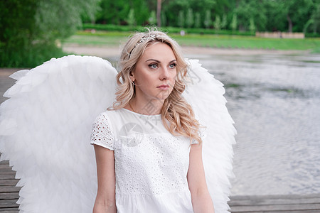迷人的金发美女 有白色天使翅膀 站在水边 美丽的女人穿着天使服装礼服翼装女孩大天使婚礼裙子宗教精神女士天堂图片