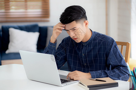 年轻的亚洲商务人士在笔记本电脑上工作时头痛 最后期限在家里的办公桌上 失败的商务人士筋疲力尽 疲倦 压力和担心 沮丧和失败工人技图片