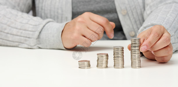 妇女坐在桌子和桌上的一叠硬币上 支出和收入 补贴 税费的计算图片