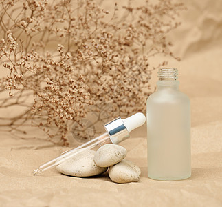 带吸管的白色玻璃瓶立在牛皮纸背景上 化妆品 SPA 品牌 凝胶包装图片