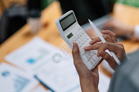 女企业家用手里拿着笔的计算器 用办公桌背景计算财务费用图片