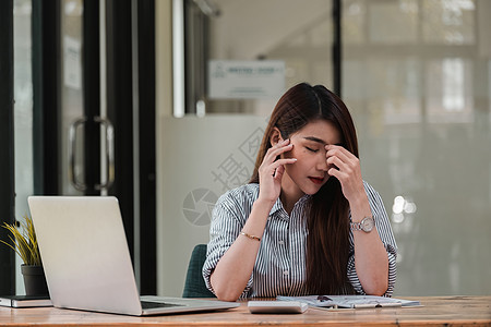 压力大的年轻女性坐在办公桌前在家办公 女商务人士头痛 同时在办公室工作时遇到问题沮丧秘书文书商务笔记本工人危机人士商业技术图片