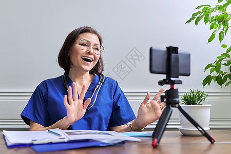使用智能手机在三脚架上在线咨询听诊器的女医生诊所家庭卫生摄像头药品专家医疗保险讲话在线互联网图片
