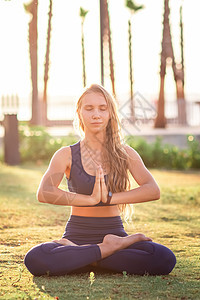 坐在Lotus的年轻女孩在日落时装扮成瑜伽练习 在靠近海滨线的公园练瑜伽头脑天空专注阳光冥想海滩平衡假期海滨太阳图片
