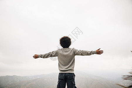 后视非洲年轻人站在山顶伸出他的手 高品质美丽的照片概念图片