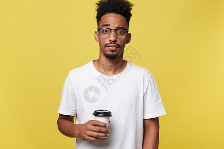 年轻时尚的美国黑人男子 拿着一杯咖啡带走咖啡 隔着黄色背景与世隔绝夹克杯子饮料男性冒充微笑太阳镜男人活动快乐图片