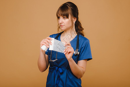 一名穿白外套的女医生在棕色背景上为伤口包扎伤口而持有扭曲的纱布绷带手套身体成人敷料帮助诊所工作职业保健卫生图片
