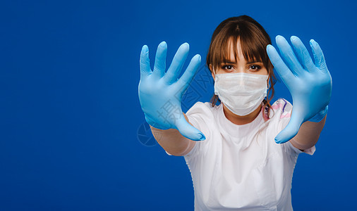 一名女医生戴着医疗面罩和手套 身着孤立的蓝色背景医院女性药品女士治疗牙医安全诊所卫生员实验室图片