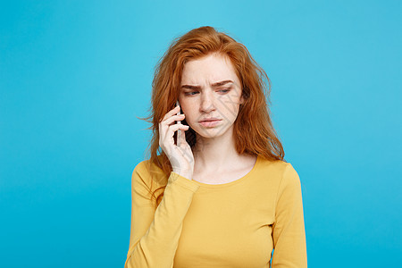 生活方式概念     姜红头发女孩的肖像 她通过手机与朋友交谈时表现令人震惊和紧张 在蓝面纸背景上孤立无援 复制空间灰色成人技术图片