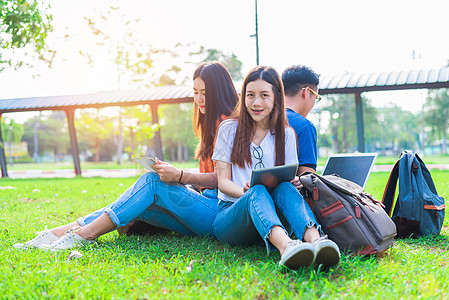 一群亚洲大学生在户外草地上使用平板电脑和笔记本电脑 技术和教育学习理念 未来科技与现代娱乐理念 寓教于乐的主题图片