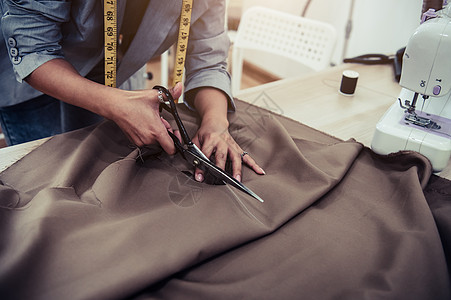 裁缝用缝纫机在素描线上裁剪礼服面料 时装设计师裁缝或下水道在车间工作室设计新系列服装 企业主商店和企业家概念图片