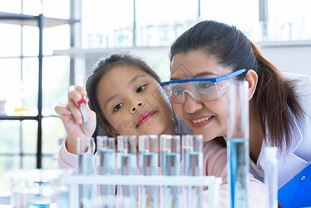 科学家女孩和老师一起用吸管将溶液物质液体滴入实验室教室的试管中 教育和科学 微米和纳米技术 电子保健和医疗概念研究医生女士管子职图片