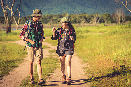 两人走在草地上的小路上 看景点观点的男性和女性旅客 情侣一起在户外探险 人与生活方式的概念 旅行和露营的主题图片