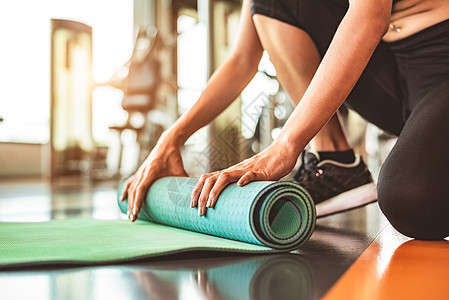 在运动健身健身房训练中心背景下特写运动型女性折叠瑜伽床垫 瑜伽课后保持运动垫滚动 锻炼和运动训练概念 手放在地毯上地面肌肉运动员图片