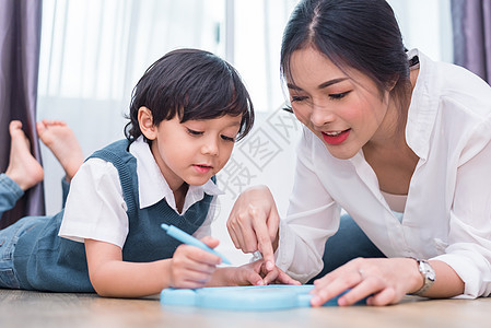 亚洲妈妈教可爱的男孩用彩色笔在板上画红心 回到学校和教育理念 家庭和家庭甜蜜的家庭主题 学龄前儿童主题 前视角图片