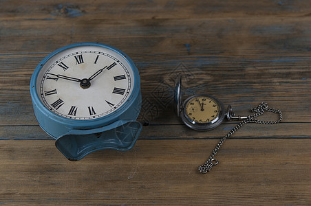 配有罗马数字的闹钟和木制桌子上的旧手表图片