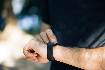 在黑色触摸屏外用现代智能手表小工具特写男性手的视图 在线检查通知 测量距离 心率 卫生保健图片