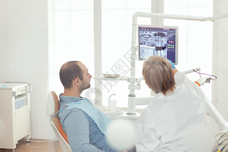 坐在牙椅上看牙齿射线摄影的病男背景图片