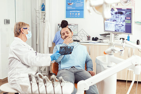高级女牙医 与生病男子一起检查牙齿放射线护士男人专家助手办公室讨论照相医师x光访问图片