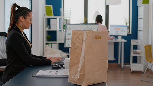 商业妇女拿着纸袋和外卖食品餐点菜单的纸袋 把桌子放在桌上邮递员图表服务办公室时间战略命令数据统计工作图片