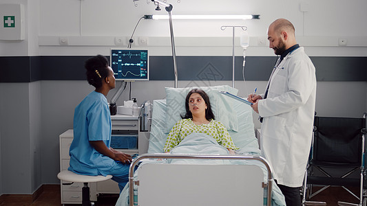 美籍女护士在分析X光骨头时躺在床上的生病妇女前视线图片