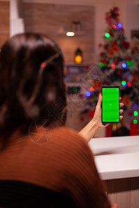 拿着有绿色屏幕的智能手机的少妇展示笔记本技术成人盒子女士庆典工具假期礼物图片