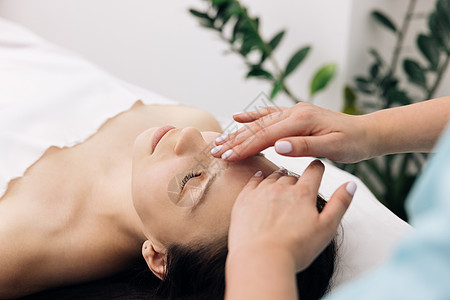 年轻的白人女性在美容 spa 沙龙接受 spa 按摩治疗 用于护肤 放松按摩 Spa 皮肤和身体护理的面部按摩精油图片