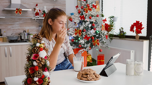 在装饰厨房的厨房里坐在桌边看平板电脑上的Xmas在线视频图片