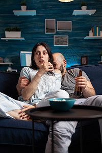 惊心动魄的夫妇在晚上看电视电影 吃爆米花手表视频情感闲暇长椅沙发啤酒享受控制器频道图片