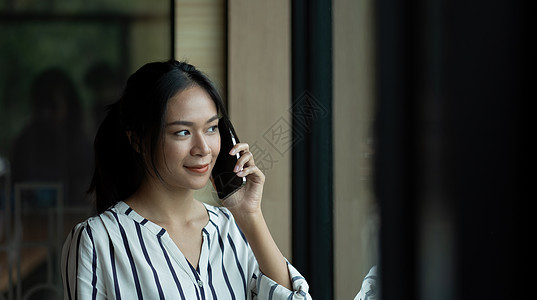 与手机上的人聊天的亚洲女青年 在她的手机上屏幕讲话商业女孩办公室黑色微笑女士女性互联网图片