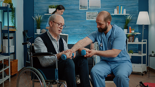 护士帮助残疾男子用哑铃锻炼运动疾病诊所照顾者专家护理服务麻痹女士药品病人图片