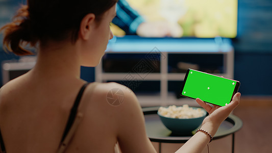 拿着有水平的绿色屏幕的现代电话的人图片