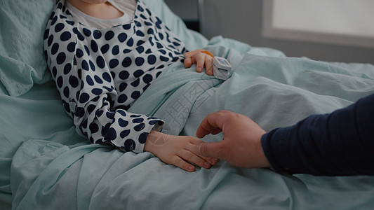 与生病的女儿坐在医院病房里 手握着双手的近亲父亲坐在一起图片