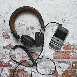 在砖墙上挂有旧按键电话的头耳机图片