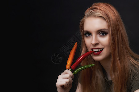 微笑的年轻美女正在品尝红辣椒图片