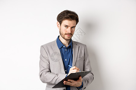穿着灰色西装 做笔记 穿办公室服装 保持剪贴板和看相机 白色背景的生意人成功广告情绪工人商务生活经理快乐工作室人士工作图片