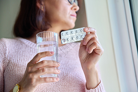 在成年妇女手中紧闭装有水杯的水的泡泡药丸药物药店保健疼痛诊断治疗玻璃症状女性饮食图片