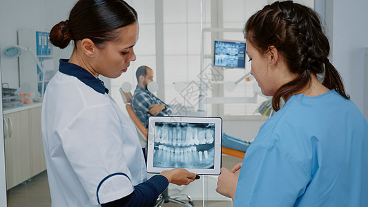 牙科医生和护士分析药片上的牙齿放射线图片