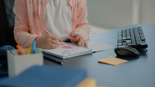 在笔记本上用彩色铅笔贴近小孩子女学生桌面桌子女孩互联网电脑班级学校技术房间图片