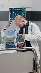 医生指着用放射线为患病妇女显示平板电脑的陈列器病房诊所女士屏幕情况医院照相保健病人外科图片